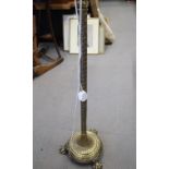 An Edwardian embossed brass standard lamp, on circular weighted base and lion paw feet