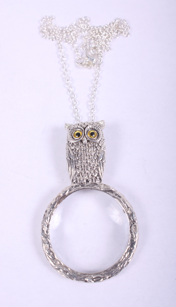 A white metal magnifying glass, formed as a perched owl, stamped 925, on white metal necklace