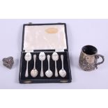 A silver christening mug with inscription, a cased set of six silver teaspoons, a white metal