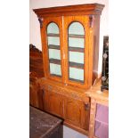 A Victorian walnut bookcase, the upper section enclosed glazed doors over drawer and cupboards, on