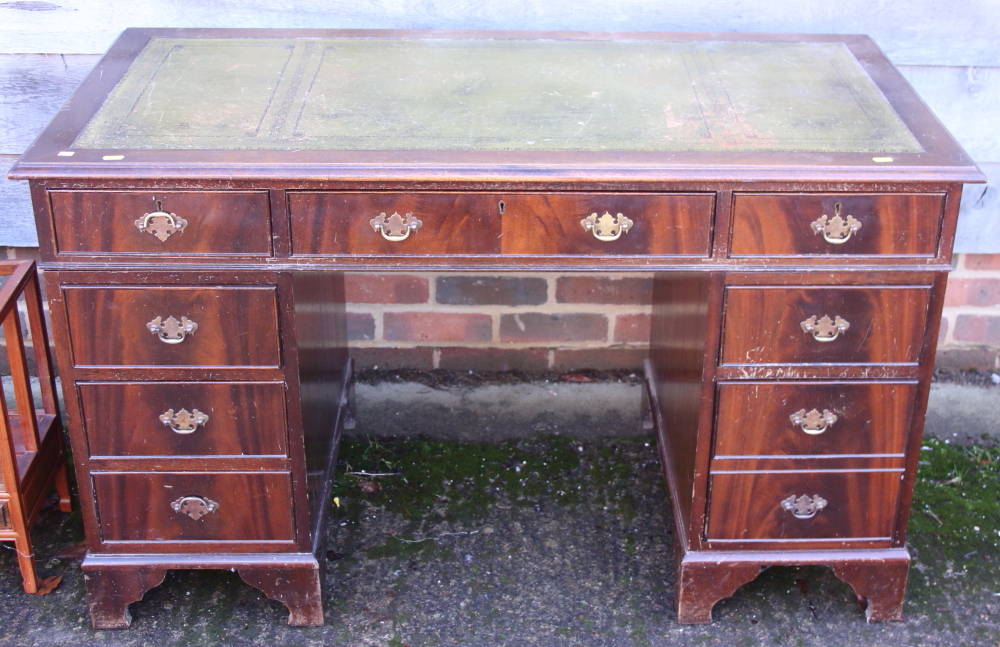 A mahogany kneehole double pedestal desk, fitted nine drawers with green leather tooled lined top,