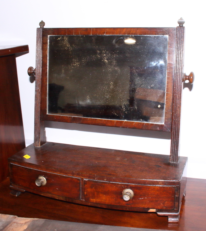 An early 19th century mahogany swing frame toilet mirror, on bowfront plateau base, fitted two