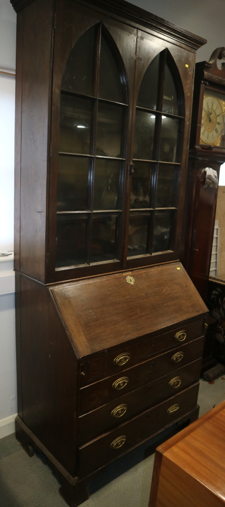 A late Georgian oak bureau bookcase, the upper section enclosed two arch top glazed doors over