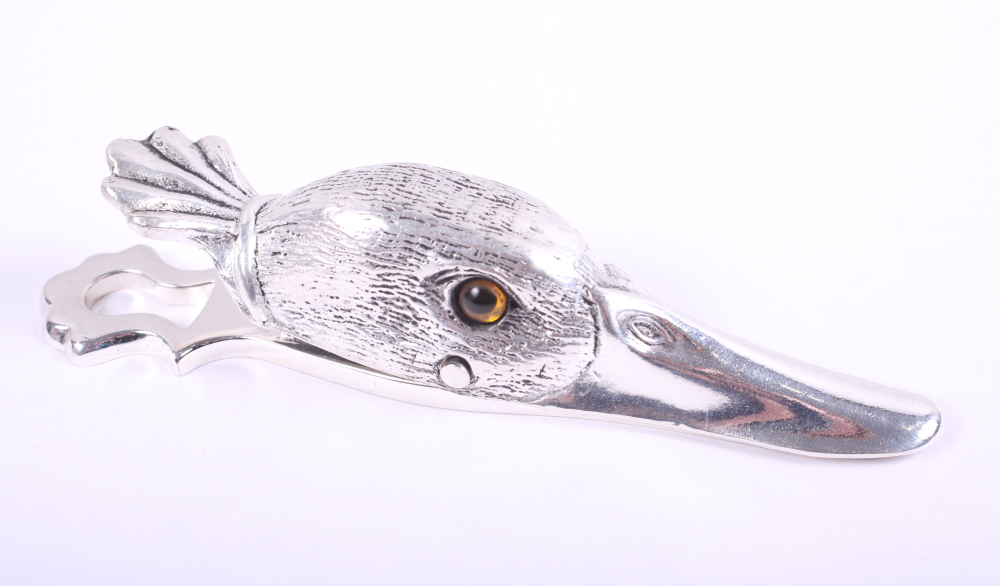 A white metal paper clip in the form of a duck's head with glass eyes