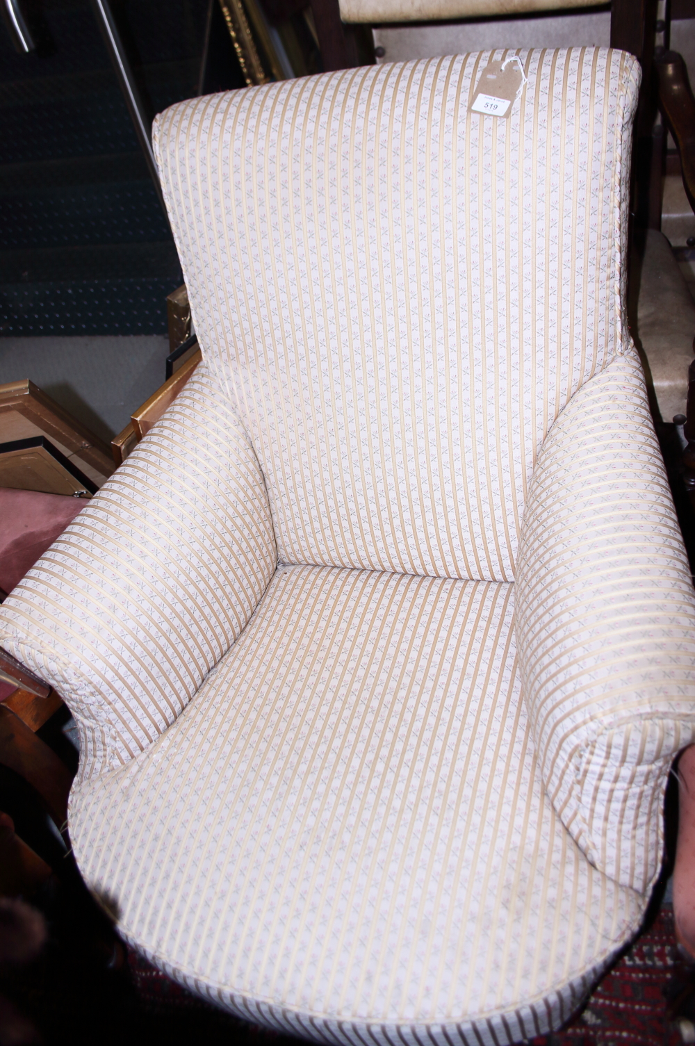 A late Victorian low armchair, upholstered in a floral fabric, on turned and castored supports