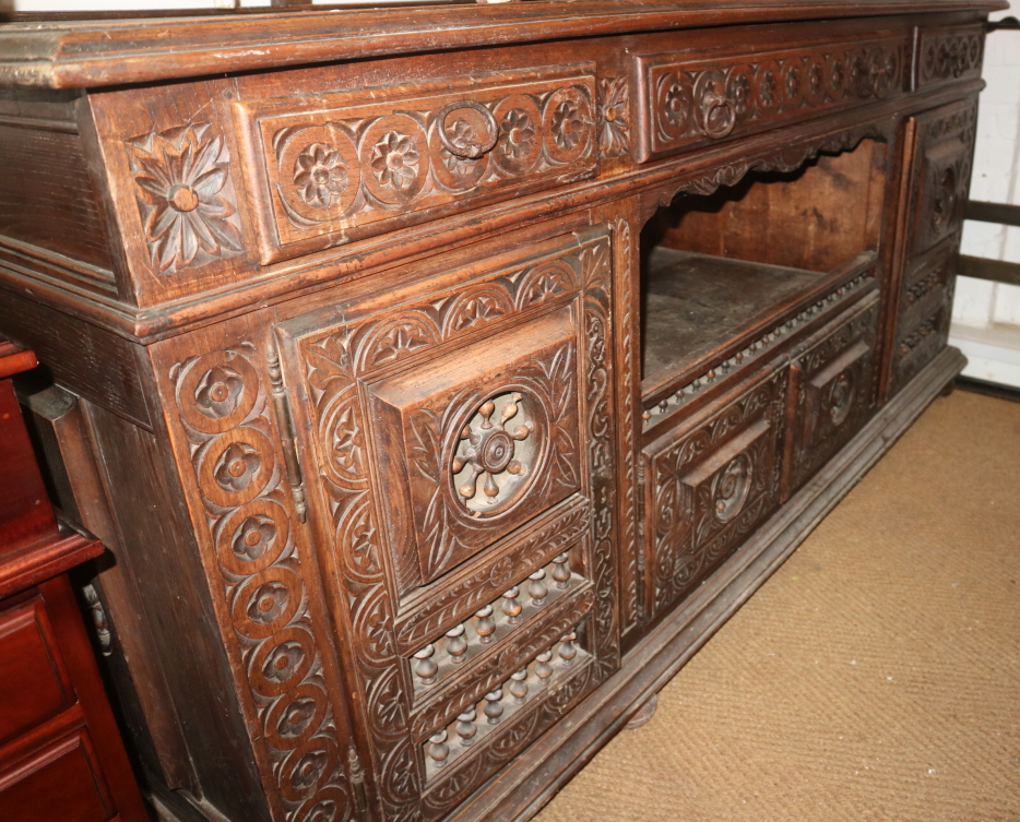 A 19th century Breton carved walnut sideboard, fitted three drawers over central recess and