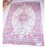 A Persian rug with central medallion and flower decoration in shades of red, blue, green and