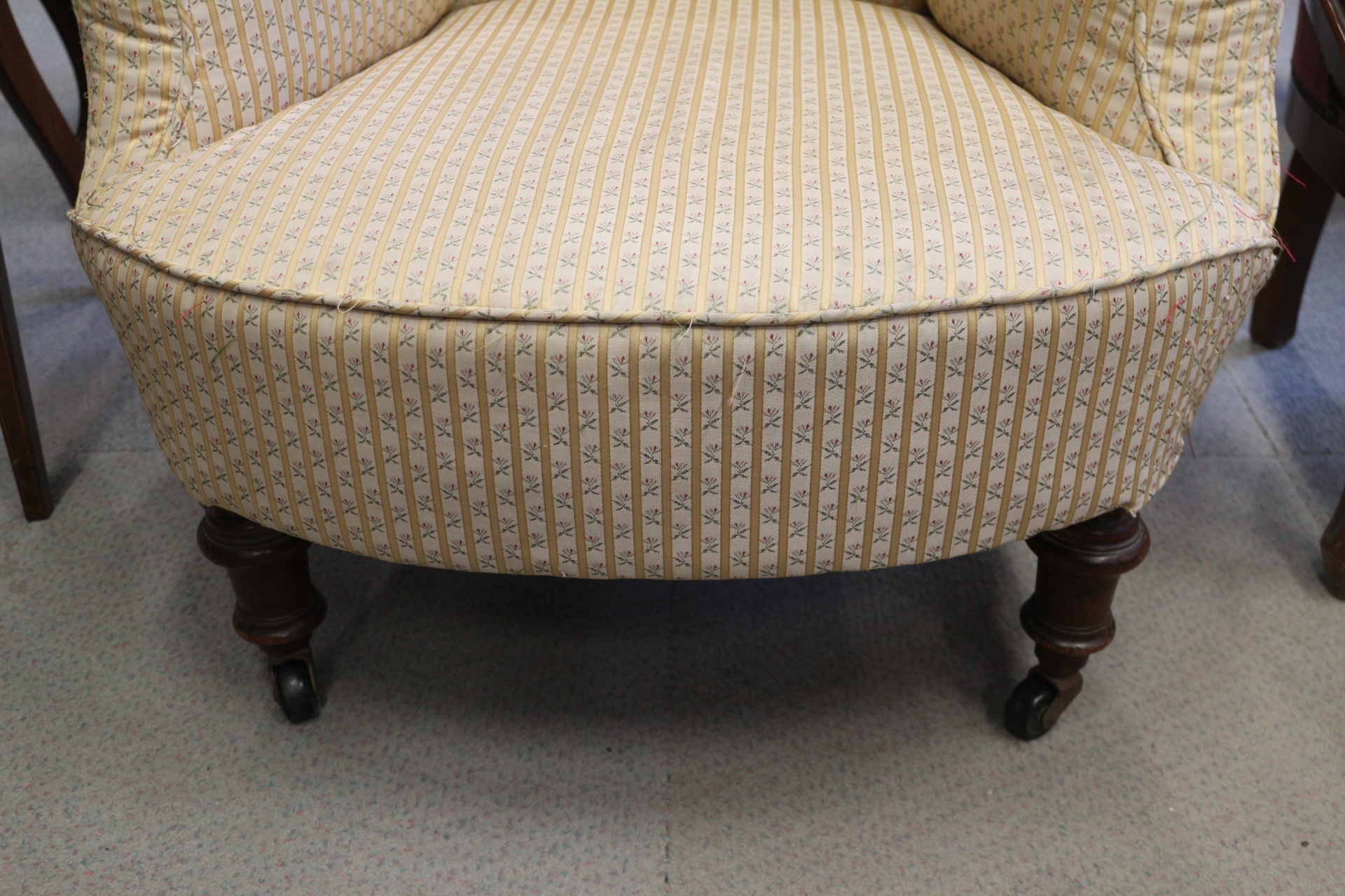 A late Victorian low armchair, upholstered in a floral fabric, on turned and castored supports - Image 2 of 3