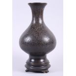 A Chinese bronze bulbous vase, decorated bats and clouds, on hardwood base, 12" high overall