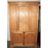 A stripped pine hall cupboard, the upper section fitted single door over two further doors, on block