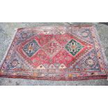 A Caucasian tribal rug with three medallions on a crimson floral ground and multi-bordered in shades