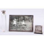 A rectangular silver photograph frame, a silver topped dressing table jar and a silver mounted match
