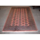 A Bokhara rug of traditional design with thirty-nine guls on a pink ground and multi-boarded in