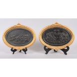 A pair of 19th century Wedgewood black basaltes oval panels, "Boar Hunt" and "Greek Gods Dining",