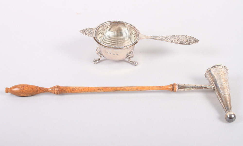 A silver tea strainer and stand, 3oz troy approx, and a silver candle snuffer with turned wooden