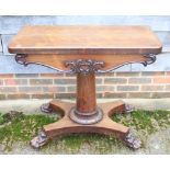 A Victorian rosewood fold-over card table with carved decoration, on turned column and quadraform