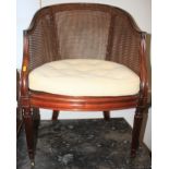 A late 19th century walnut bergere tub-shape armchair with loose seat cushion, on reeded castored