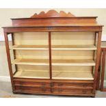 A walnut bookcase with raised back enclosed two glazed doors and fitted four short drawers, on bun