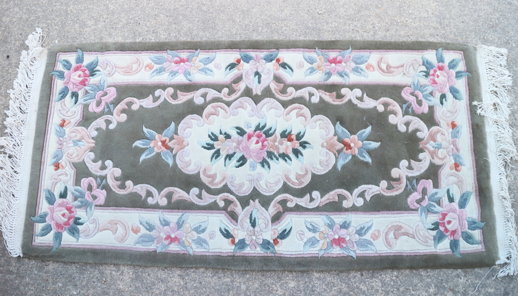 A Chinese contour pile rug with floral design and green border, 48" x 20" approx