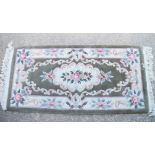 A Chinese contour pile rug with floral design and green border, 48" x 20" approx