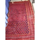 A Middle Eastern geometric design rug on a red ground with multi-borders in shades of blue, 63" x 43