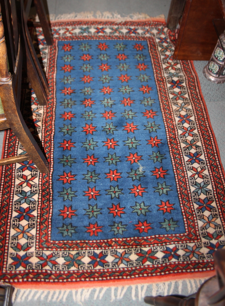 A Caucasian wool geometric design rug with central decoration of fourteen rows of five guls on a red