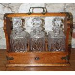 An early 20th century oak and metal mounted three-decanter Tantalus