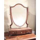 A mahogany shield-shaped swing frame toilet mirror of Sheraton design, on serpentine base, fitted