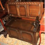 A monks oak bench with carved lion armrests and panelled design, on bracket supports, 41 1/2" wide