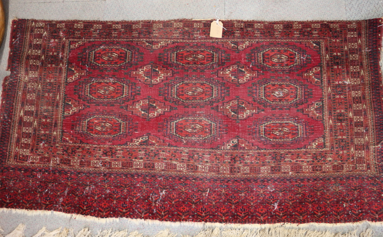 A Bokhara bag face rug with nine octagonal guls in traditional colours, 60" x 30" approx (worn)