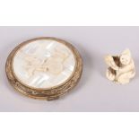 A carved ivory netsuke, formed as a crouching figure, and a powder compact, decorated with a