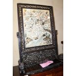 A late 19th century Chinese carved hardwood fire screen with bird embroidered panel, on splay