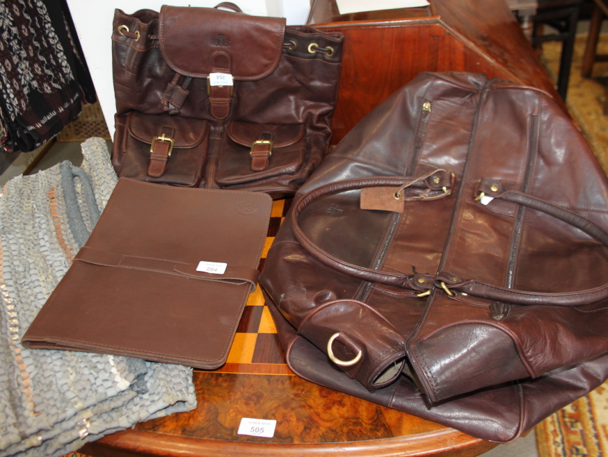 A Rowallan brown leather travel bag, a similar rucksack, an Estero brown leather folio and a leather