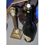 A 19th century brass Corinthian column candlestick, 20" high, and a green glass wine bottle, 24"