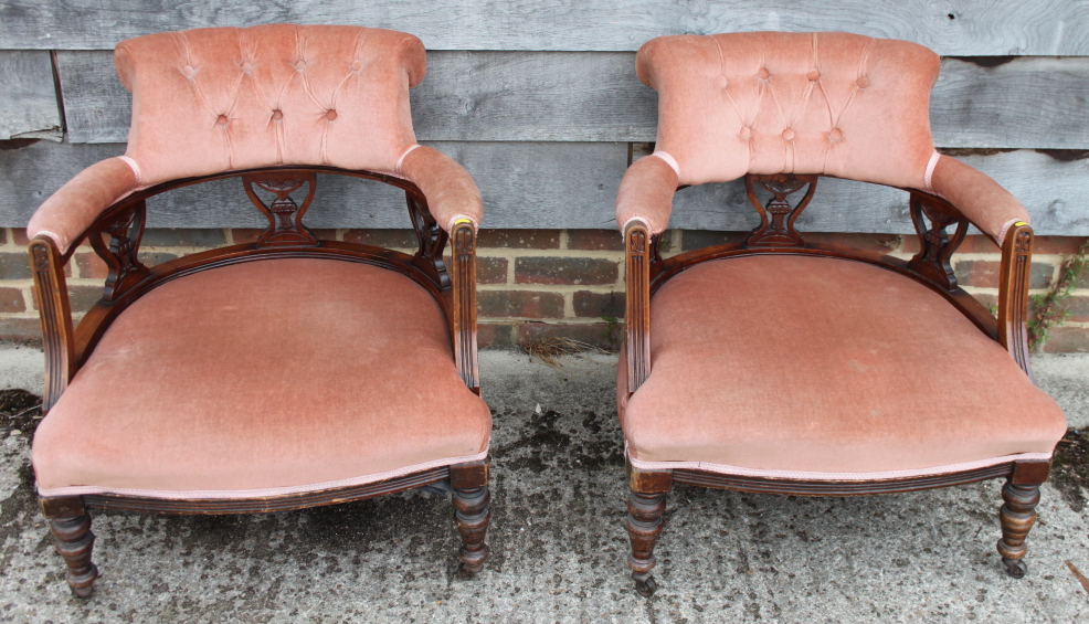A pair of early 20th century low seat chairs, button upholstered in a pink fabric, on turned