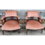 A pair of early 20th century low seat chairs, button upholstered in a pink fabric, on turned