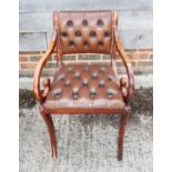 A polished as mahogany desk elbow chair of Regency design, button upholstered in a red leather