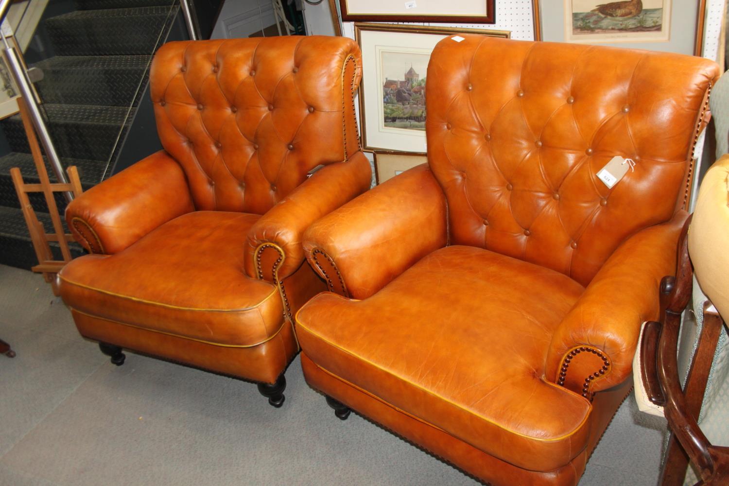 **A pair of brown leather button back armchairs, on turned supports (**Please note this lot is