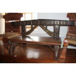 An Indian hardwood low bench with brass and metal decorative fittings made from an ox yoke, 54" wide