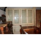 A cream painted pine library bookcase, the upper section enclosed four glazed doors over two reading