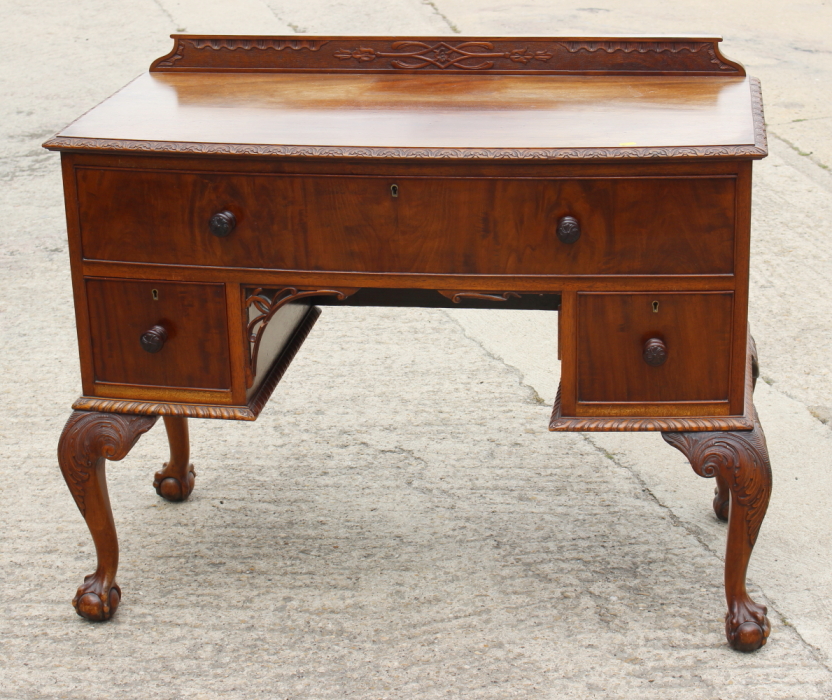 A walnut bowfront desk, fitted one long and two deep drawers, on carved cabriole claw and ball
