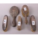 Four silver dressing table brushes and a silver hand mirror