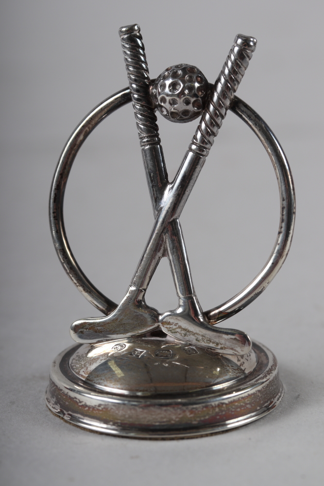 A silver golf club menu holder, on weighted base