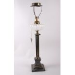 An anodised brass oil lamp with cut glass reservoir and reeded column, on stepped base