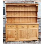 A waxed pine dresser, the upper section fitted open plate shelves over three drawers and three