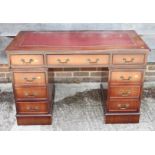 A mahogany serpentine front pedestal desk with tooled leather top, fitted nine drawers, on block