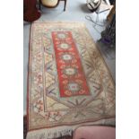 A Kazak type rug with rust centre ground and geometric borders, 79" x 46" approx