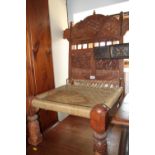 A pair of Indian sheesham low chairs with carved decorative backs and rush seats, on turned carved