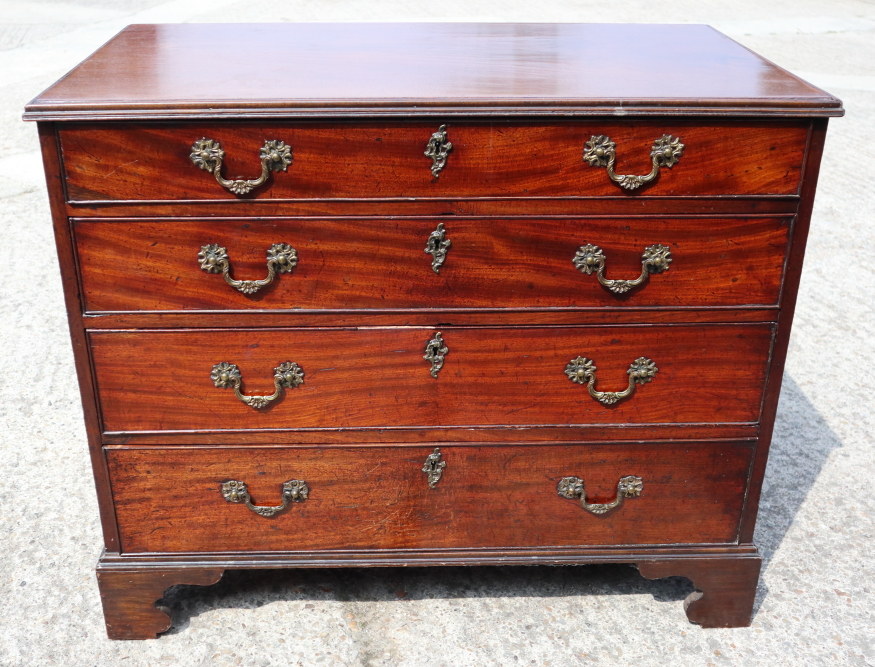 A George III mahogany chest of four long graduated drawers with gilt brass scroll handles, on