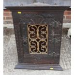 A 19th century carved oak corner cupboard, inscribed RTP 1883, with wrought iron grille door, 20"